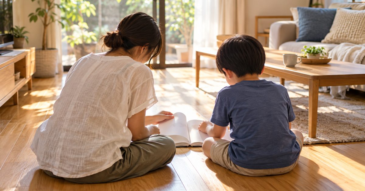 リビングの床で本を読む親子の後ろ姿